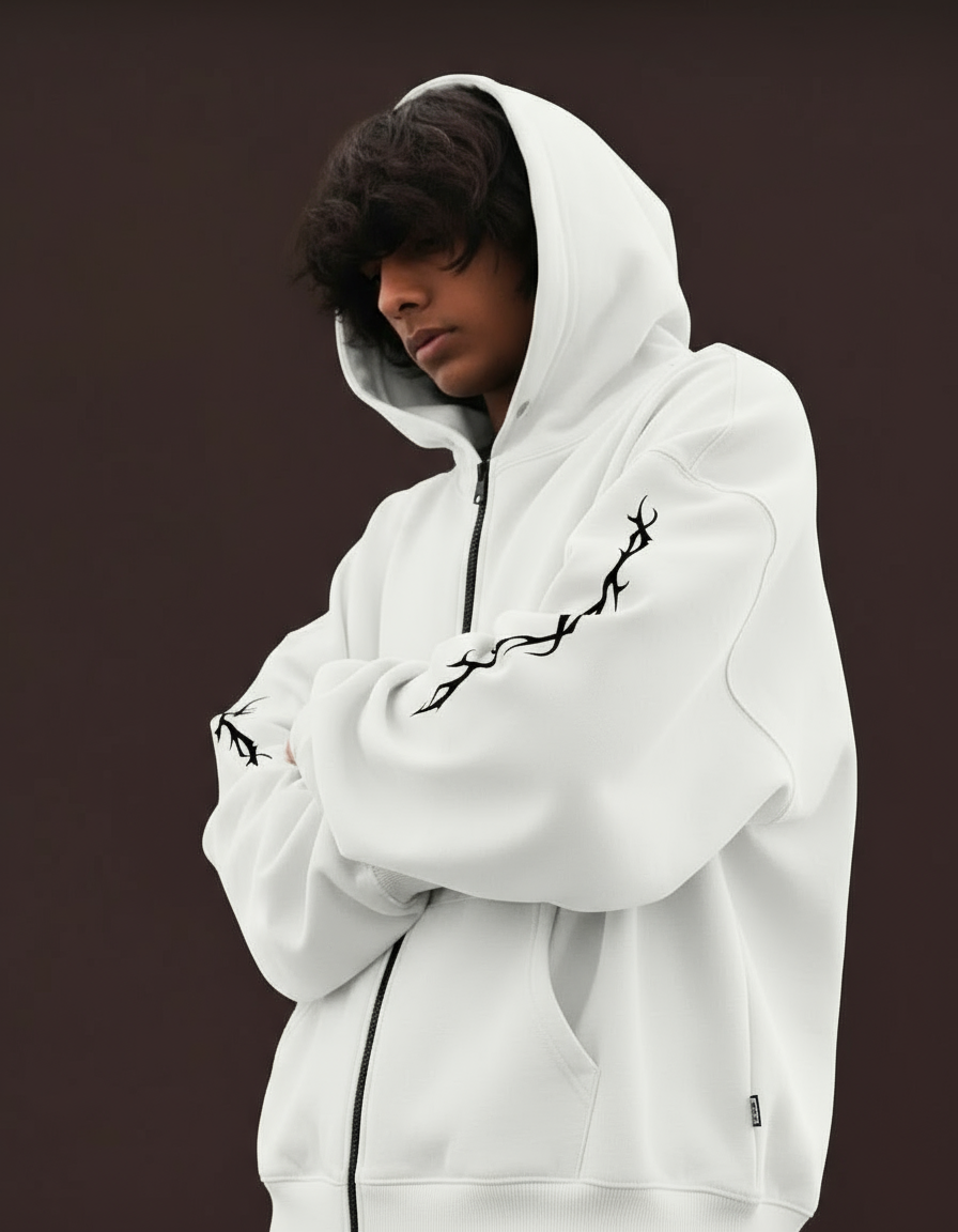 Person wearing a white hoodie with black designs on a dark background
